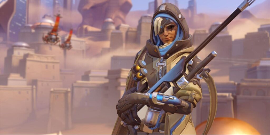Overwatch 2 support hero Ana in tactical gear holding a rifle, standing in a desert city environment
