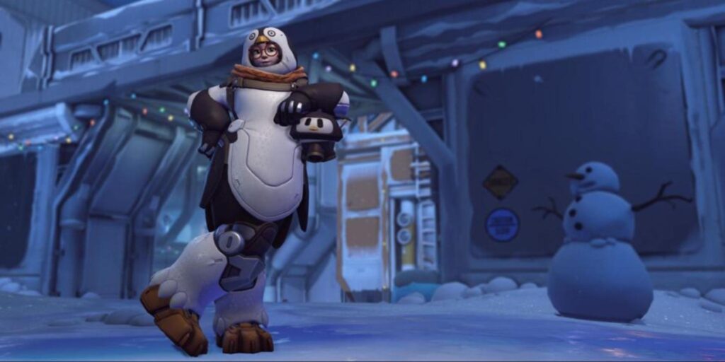 Mei in her Penguin skin from Overwatch 2, wearing a full-body penguin costume with flippers and winter boots, standing in a snowy base with a snowman in the background