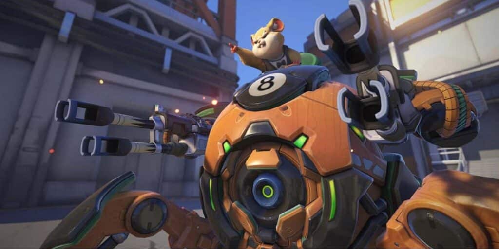 Overwatch 2 hero Wrecking Ball, a hamster piloting a spherical mech with cannons, seen in an outdoor industrial map setting.