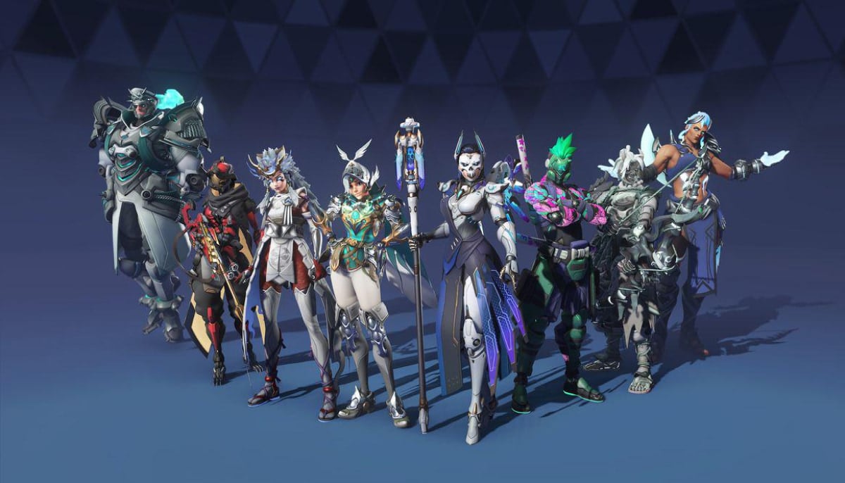 A group of nine diverse, futuristic characters of Overwatch 2 in vibrant, detailed costumes. They stand confidently, each sporting unique armor and weapons