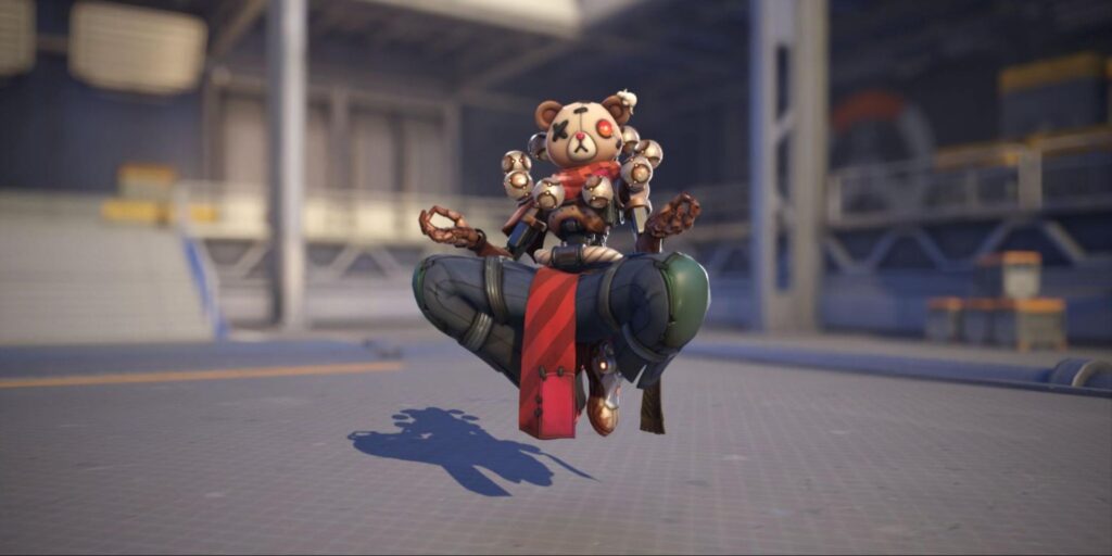 Zenyatta in teddy bear skin sits cross-legged, levitating in an industrial setting