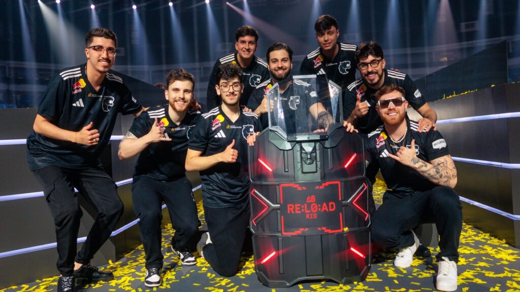 Image of FURIA Rainbow Six team posing with the RE:L0:AD trophy on a stage covered in yellow confetti